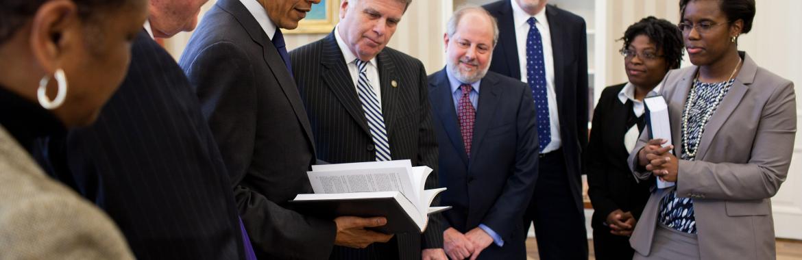 President Barack Obama receives a leather-bound 2009 edition of the "Public Papers of the Presidents of the United States" from David S. Ferriero, Archivist of the United States, center, in the Oval Office, Feb. 25, 2011. Joining them are staff from the Office of the Federal Register and National Archives and Records Administration.