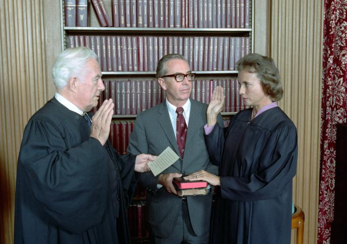 Sandra Day O'Connor being sworn in as a Supreme Court Justice by Chief Justice Warren Burger as her husband John O'Connor looks on, September 25, 1981. (NAID 276563289)