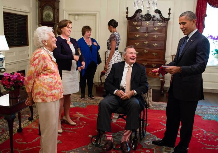 Former President George H. W. Bush and former First Lady Barbara Bush present President Barack Obama with a pair of socks in the Map Room of the White House, July 15, 2013.