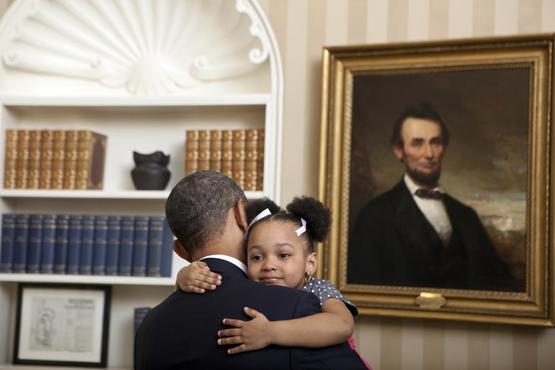 President Barack Obama greets National Security Staff (NSS) for departure photos in the Oval Office, February 1, 2012. Arianna Holmes, age 3, hugs President Obama before taking a departure photo with her family in the Oval Office of the White House. 