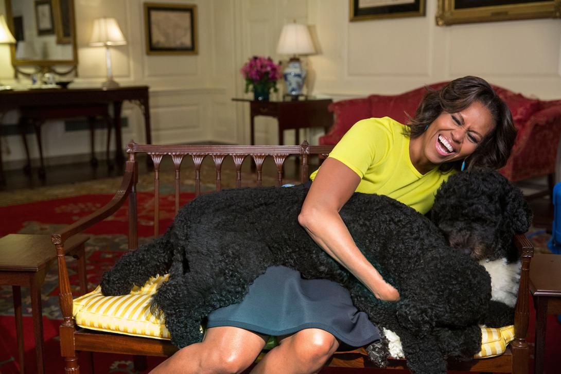 First Lady Michelle Obama hugs family pets Sunny and Bo, right, during a video taping in the Map Room of the White House, April 14, 2014.