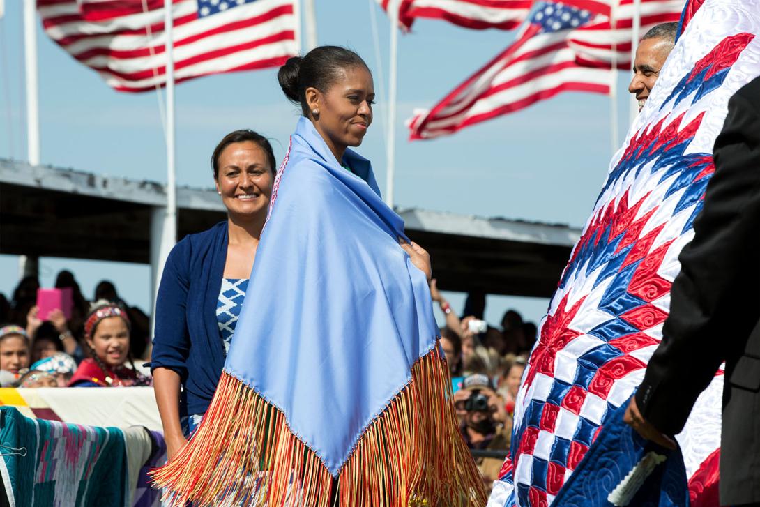 While visiting Standing Rock Sioux Tribe Reservation in Cannon Ball, North Dakota, First Lady Michelle Obama wears a shawl presented to her by Tribe Chairman Dave Archambault II and Mrs. Nicole Archambault during the Cannon Ball Flag Day Celebration, June