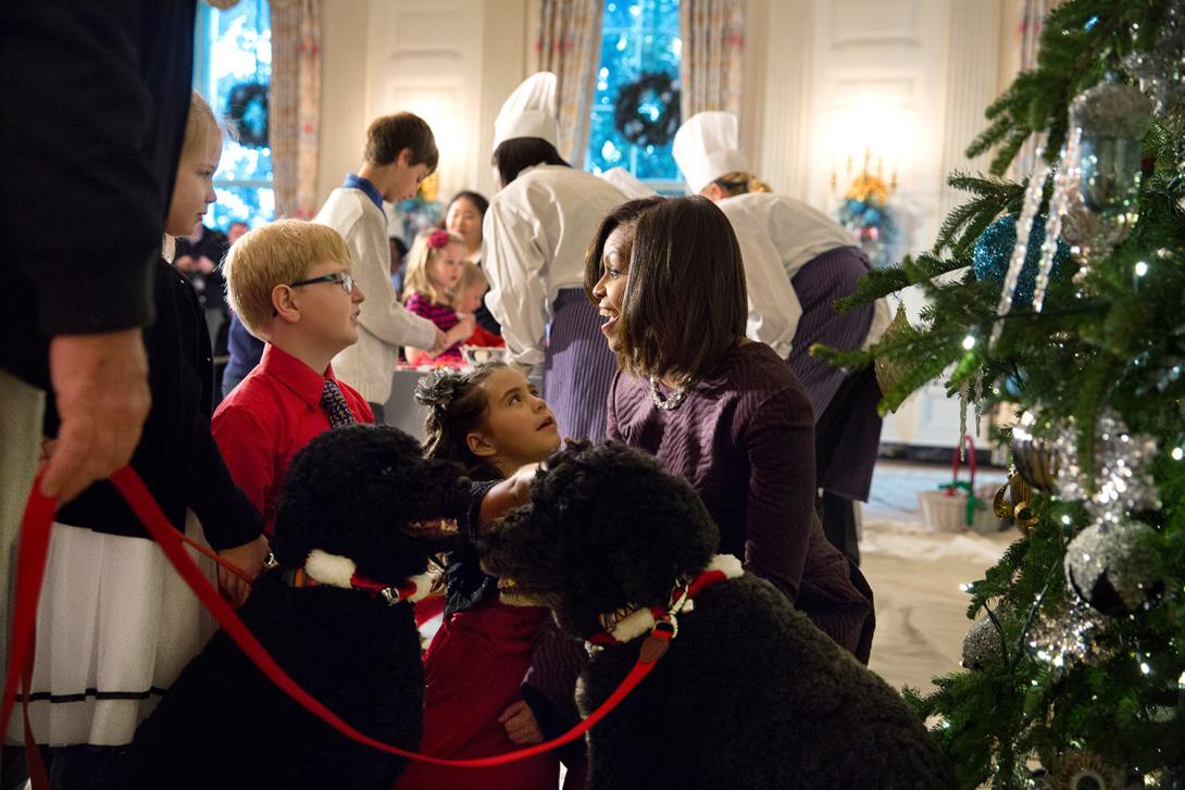 First Lady Michelle Obama, with family pets Sunny and Bo, visit with children of military families during a craft project in the State Dining Room of the White House, December 3, 2014. 